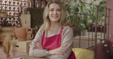 Portrait of owner of small business. Businesswoman wearing apron owner of flower shop smiling at camera inside store. A middle aged female entrepreneur smiling at camera