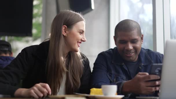 Unga Skiftande Par Sitter Caféet Och Tittar Telefonskärmen Tillsammans Glada — Stockvideo