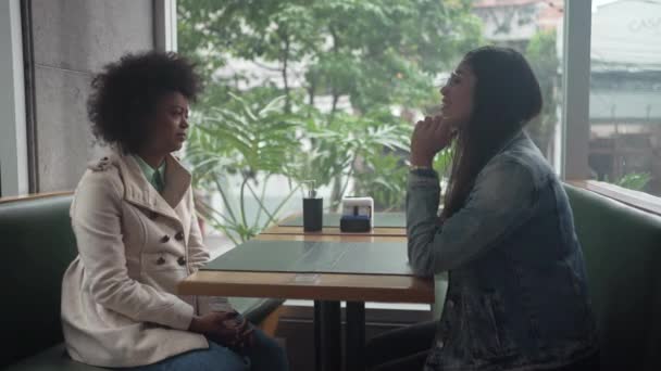 Dwie Młode Zróżnicowane Kobiety Siedzą Kawiarni Rozmawiają Ludzie Kawiarni Rozmawiają — Wideo stockowe