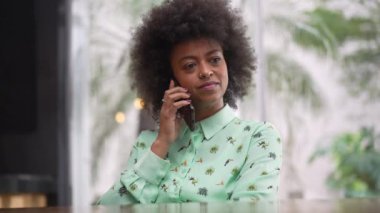 Afrikalı Amerikalı bir kadın cep telefonuyla bir telefon görüşmesi yapıyor. Kahve dükkanında oturan siyah bir kız akıllı telefon cihazıyla konuşuyor.