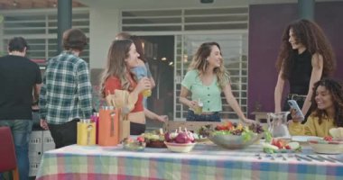 Bir grup arkadaş evin arka bahçesindeki barbekü partisinde sohbet ediyorlar. Masada oturan herkes gülüyor ve mutlu..