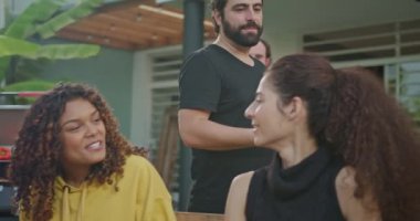 Bir grup arkadaş evin arka bahçesindeki barbekü partisinde sohbet ediyorlar. Masada oturan herkes gülüyor ve mutlu..
