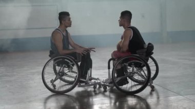 Tekerlekli sandalyede konuşan iki engelli sporcu. Spor giyimli engelli basketbolcular