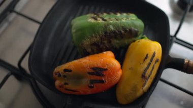 Tavada biber pişirmek. Kızarmış kırmızı yeşil ve sarı biber.