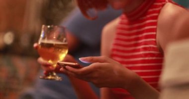  Gizli kadın elleri cep telefonunu tutuyor, parmaklarıyla sallıyor ve barda bira içiyor..