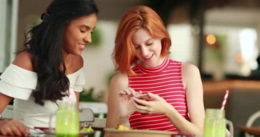 İki çok ırklı arkadaş cep telefonu ekranına bakıyor.