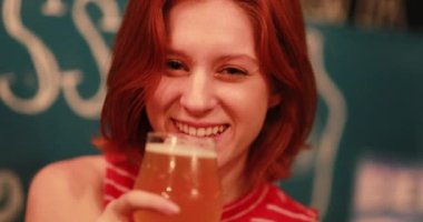 Güzel kızıl saçlı genç kadın barda bira içiyor.