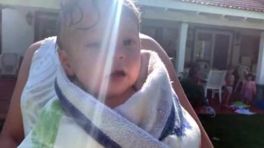 Güneşin altında kuruyan havlunun etrafına sarılmış şirin bir bebek.