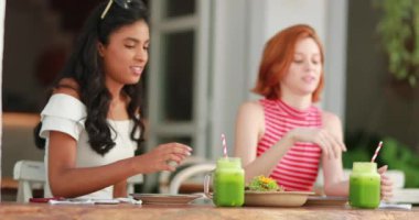 Çok ırklı arkadaşlar yeşil meyve suyu içiyor. Çoklu etnik arkadaşlığın sebze suyu şakırdıyor.