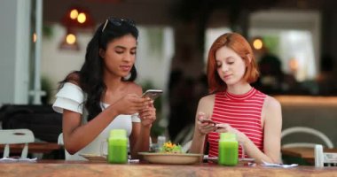 Çok kültürlü kızlar cep telefonu cihazıyla yemek fotoğrafı çekiyor. Restoranda oturan bayan arkadaşlar..