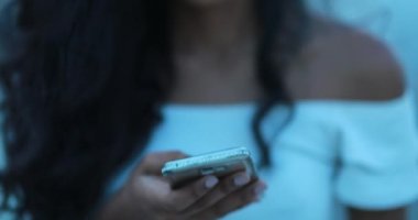 Cep telefonu tutan ve kamera önünde gülümseyen bir kız. Akıllı telefon tutan ve gülümseyen genç bir kadın.
