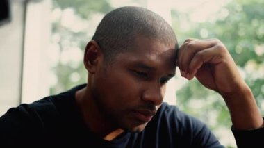 Üzgün suratlı, depresif, yakından bakan biri. Afrikalı Amerikalı adam.