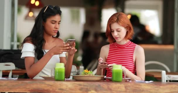 Красивые Многорасовые Девушки Фотографируют Тарелку Едой Смартфонами Сидя Зелеными Соками — стоковое видео