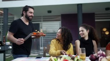 Barbekü şefi barbekü partisinde arkadaşlarına ve ailesine yemek servisi yapıyor. Tatilleri birlikte kutlayan bir grup mutlu insan.