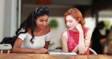 Menüye bakan iki çok ırklı genç kadın.