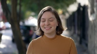 Portrait of a happy young woman walking in city sidewalk. Millennial girl in 20s walks forward feeling confidence