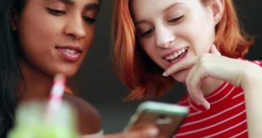 İki farklı ırktan kız cep telefonu ekranına bakıyor..