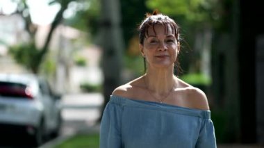 Şehir sokaklarında kameraya gülümseyen mutlu yaşlı bir kadının portresi.