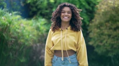 Sarı bluz ve açık havada duran mavi kot giyen kıvırcık saçlı, modaya uygun, Afro-Amerikan bir kız. Gülümseyen siyah Latin 20 'li yaşlarda bir kadın.
