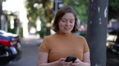 Person checking phone while walking outside in city street. Young woman looking at cellphone in urban sidewalk looking for map directions