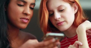 İki kız cep telefonu ekranını kontrol ediyor