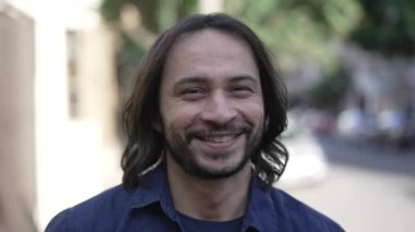 Confident hispanic man closeup face smiling walking in city urban street