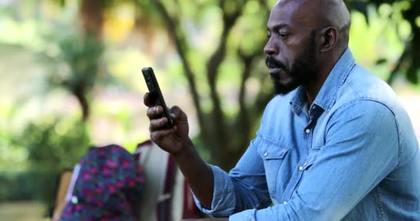 Afrikansk Man Läser Meddelande Mobiltelefon Enhet Utanför Parken Allvarligt Uttryck — Stockvideo