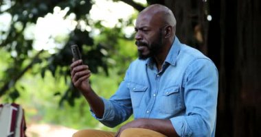 Mutlu Afrikalı adam akıllı telefonu elinde tutarak başarısını kutluyor