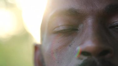 Afrikalı adam meditasyonda gözlerini kapatıyor ve dışarıda derin derin düşünüyor, makro-yakın gözler.