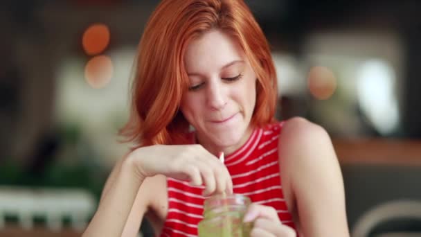 Pensive Beautiful Red Hair Girl Holding Green Juice Stirring Straw — Stock Video