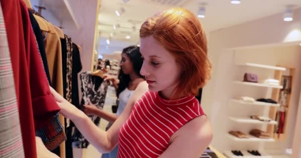 Mujer Joven Comprando Ropa Tienda Pelirroja Chica Bonita Elegir Qué — Vídeo de stock