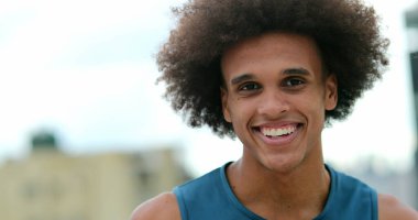 Happy african man walking at night holding cellphone laughing and smiling at content