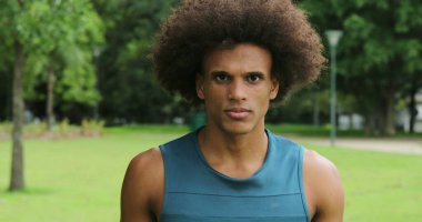 Mixed race man walking forward towards camera portrait serious at park