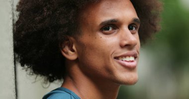 Happy young mixed race man smiling looking up at sky feeling faith and hope