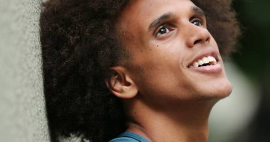 Happy young mixed race man smiling looking up at sky feeling faith and hope