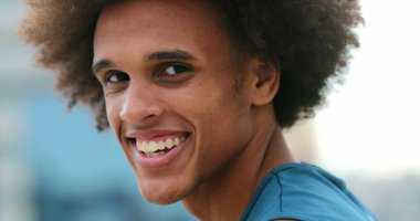 Portrait of handsome young african mixed race man smiling to camera feeling joy. Confident black man turning head towards camera