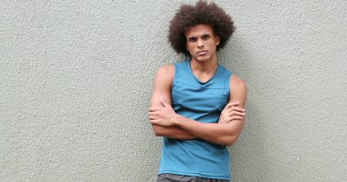 Young african american man leaning on wall with arms crossed