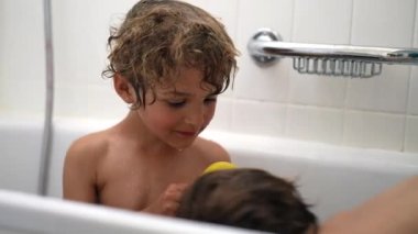 Çocuklar banyo yaparken su sıçratıyor. Banyo yapan iki küçük çocuk su sıçratıyor.