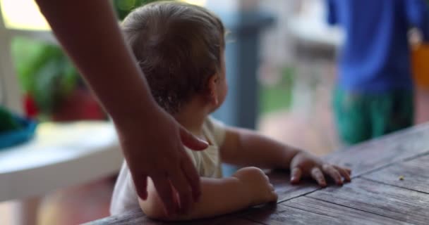 蹒跚学步的小孩抱着木桌学习站立和走路 — 图库视频影像