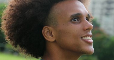 Young african black man opening eyes looking up to the sky feeling happy and smiling 