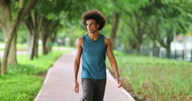 Young black handsome african man walking at park pathway