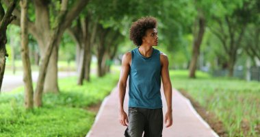 Young black handsome african man walking at park pathway