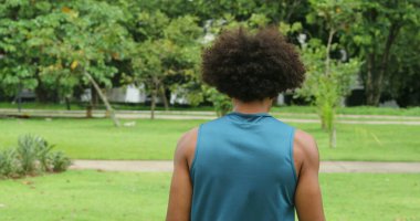 Young african with afro hair man walking at park outside