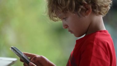 Küçük çocuk cep telefonu kullanıyor. Akıllı telefon ekranına bakan çocuk