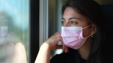 Trendeki yolcu renkli maske takıyor. Cerrahi maskeli bir kadın nakliye aracında