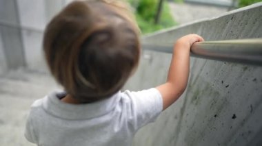 Merdivenlerden inen çocuk elinde tırabzan tutuyor.