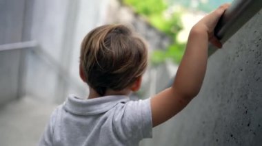 Merdivenlerden inen çocuk elinde tırabzan tutuyor.