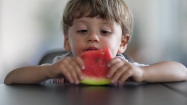 Küçük çocuk karpuz meyvesi yiyor. Çocuk sağlıklı meyve tatlısı yiyor.