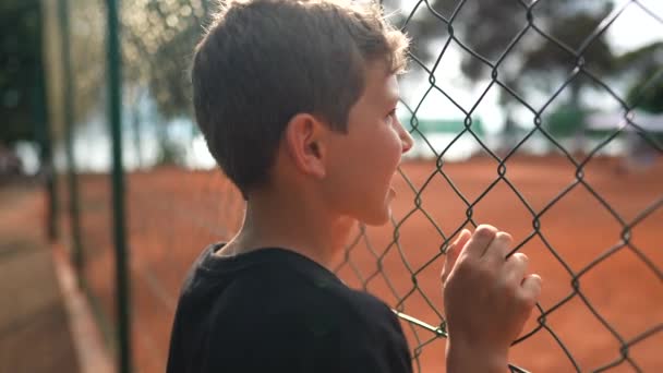 Παιδί Ακουμπά Στο Φράχτη Αγώνα Τένις Βλέποντας Σπορ Παιχνίδι — Αρχείο Βίντεο
