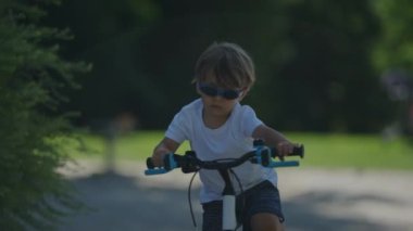Dışarıda bisiklet süren gözlüklü havalı bir çocuk.